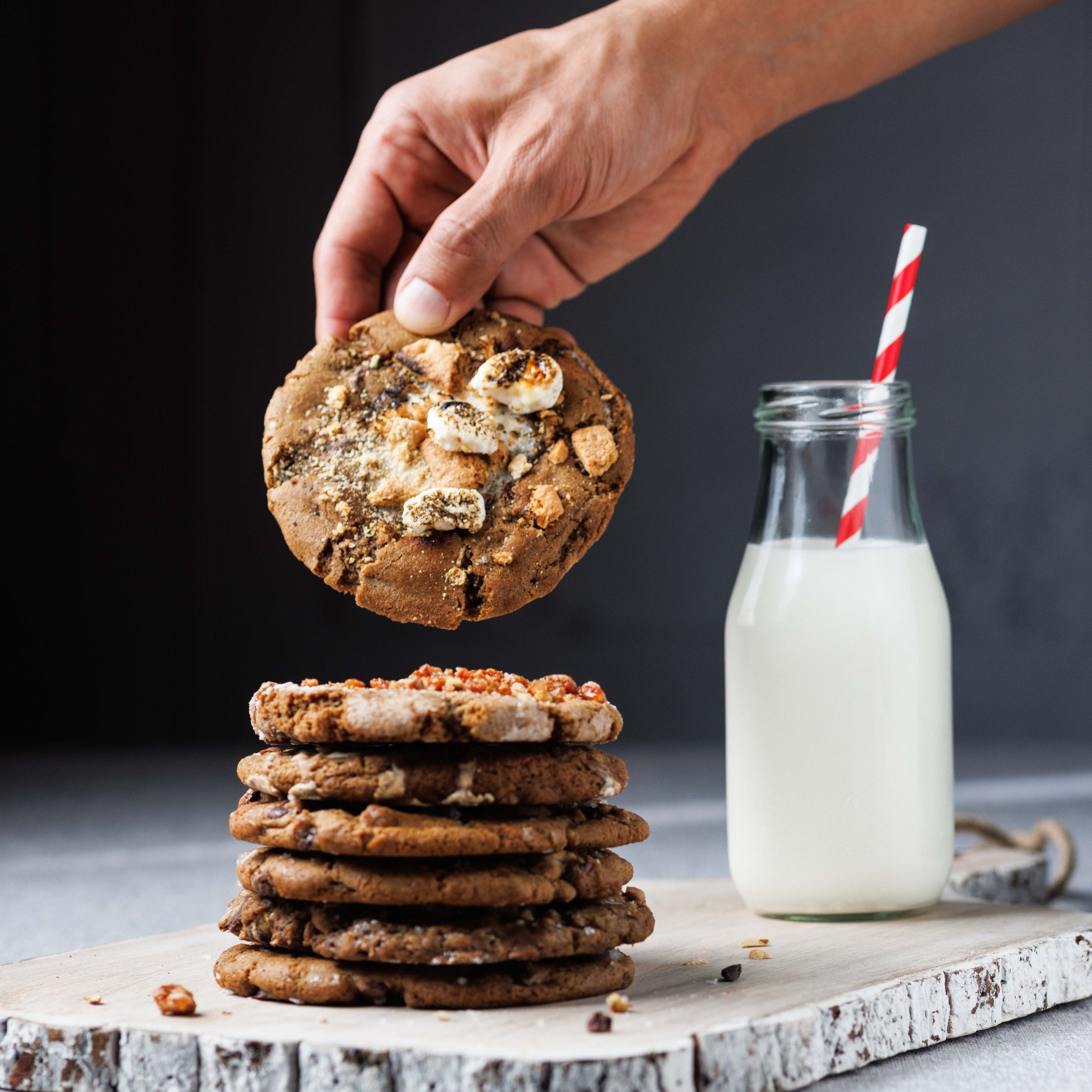 Gooey Smores cookie dipping into milk. best gooey smores s'mores cookie in san diego, best cookies in la jolla, best baked goods san diego, best bakery san diego, chewy chocolate chip cookies for shipping, cookie delivery, gourmet cookies, chef crafted flavors, at the la jolla open aire market